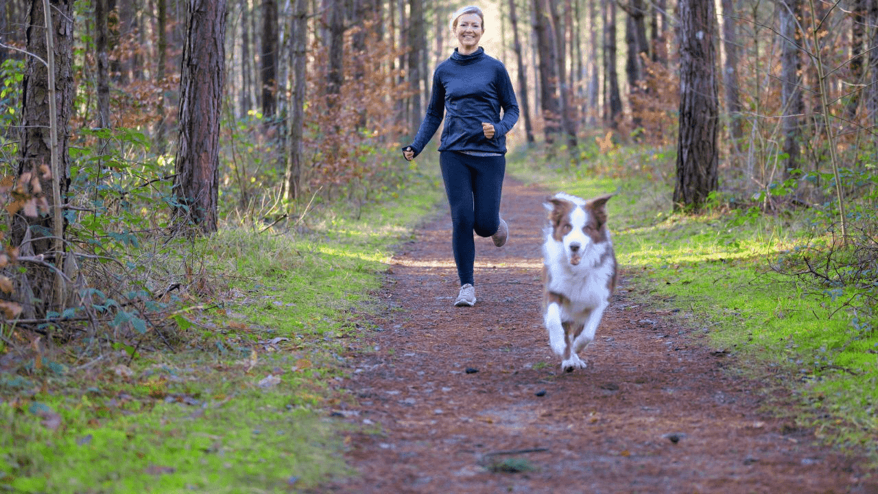 woman jogging with dog in front of her