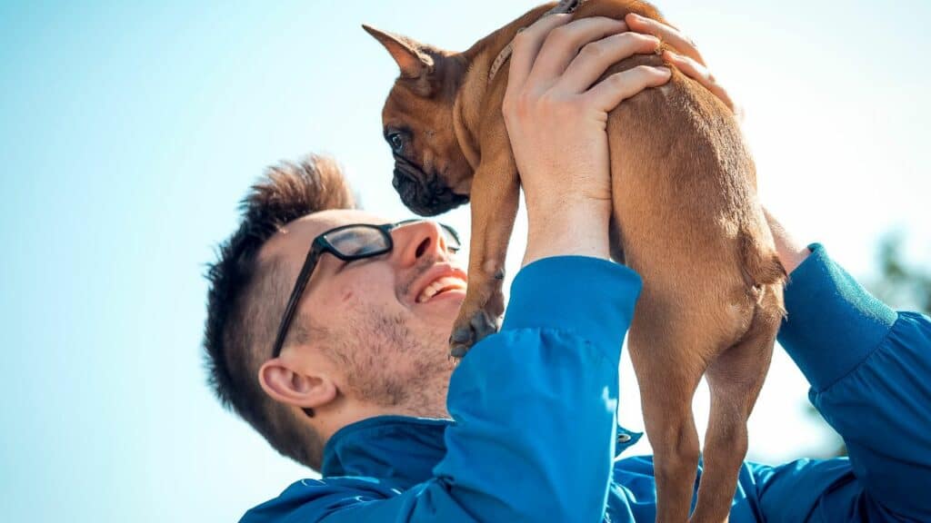 man holding brown dog in the air