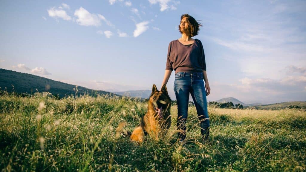 woman and a dog on grass from far away